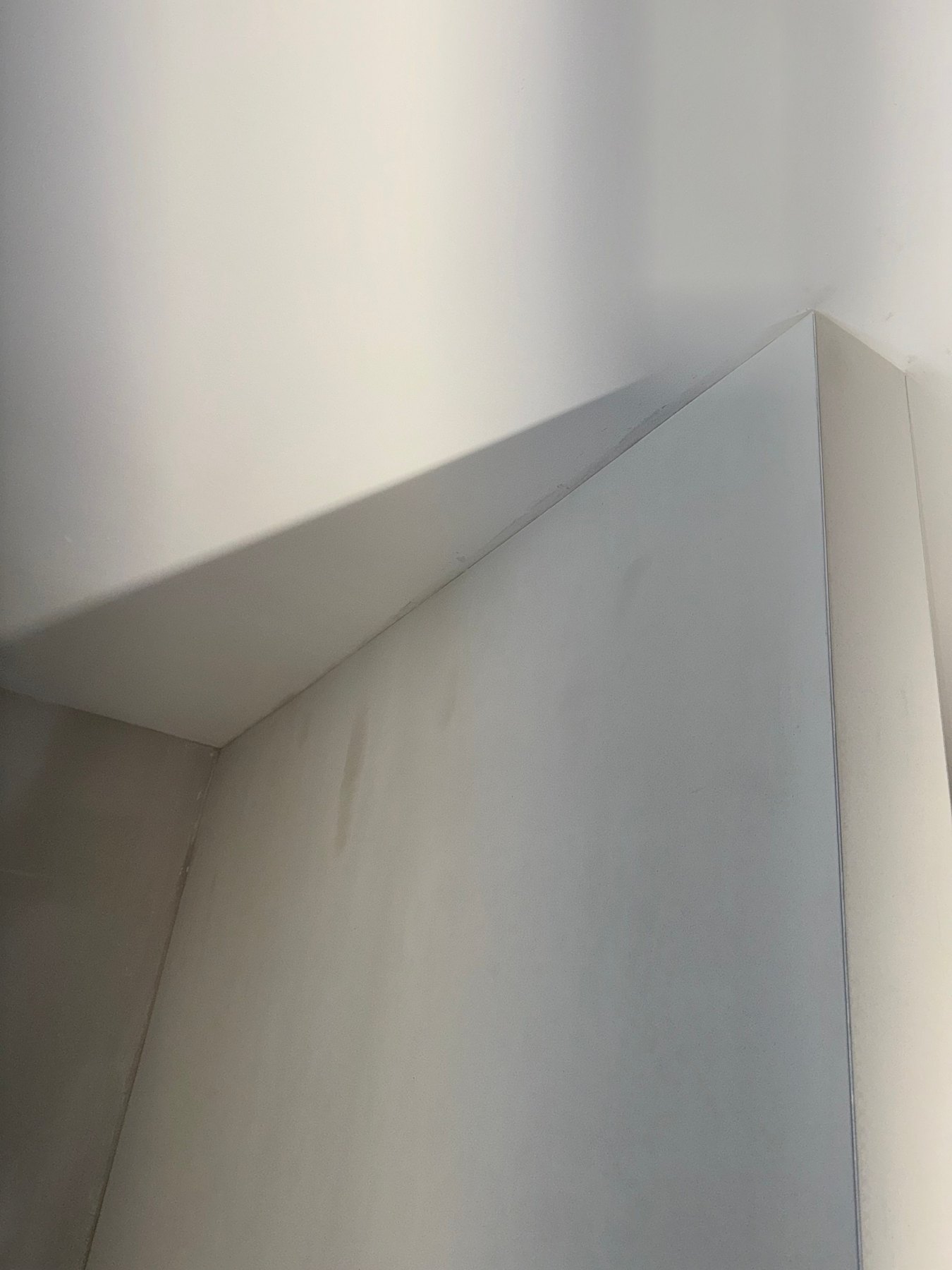 Wit geschilderd plafond en wand met een scherpe hoek
