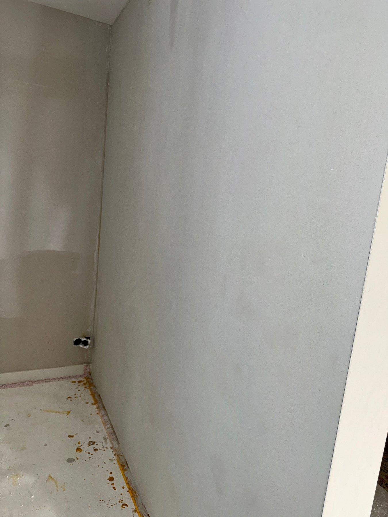 Pas gepleisterde grijze wand met afgeplakte vloer