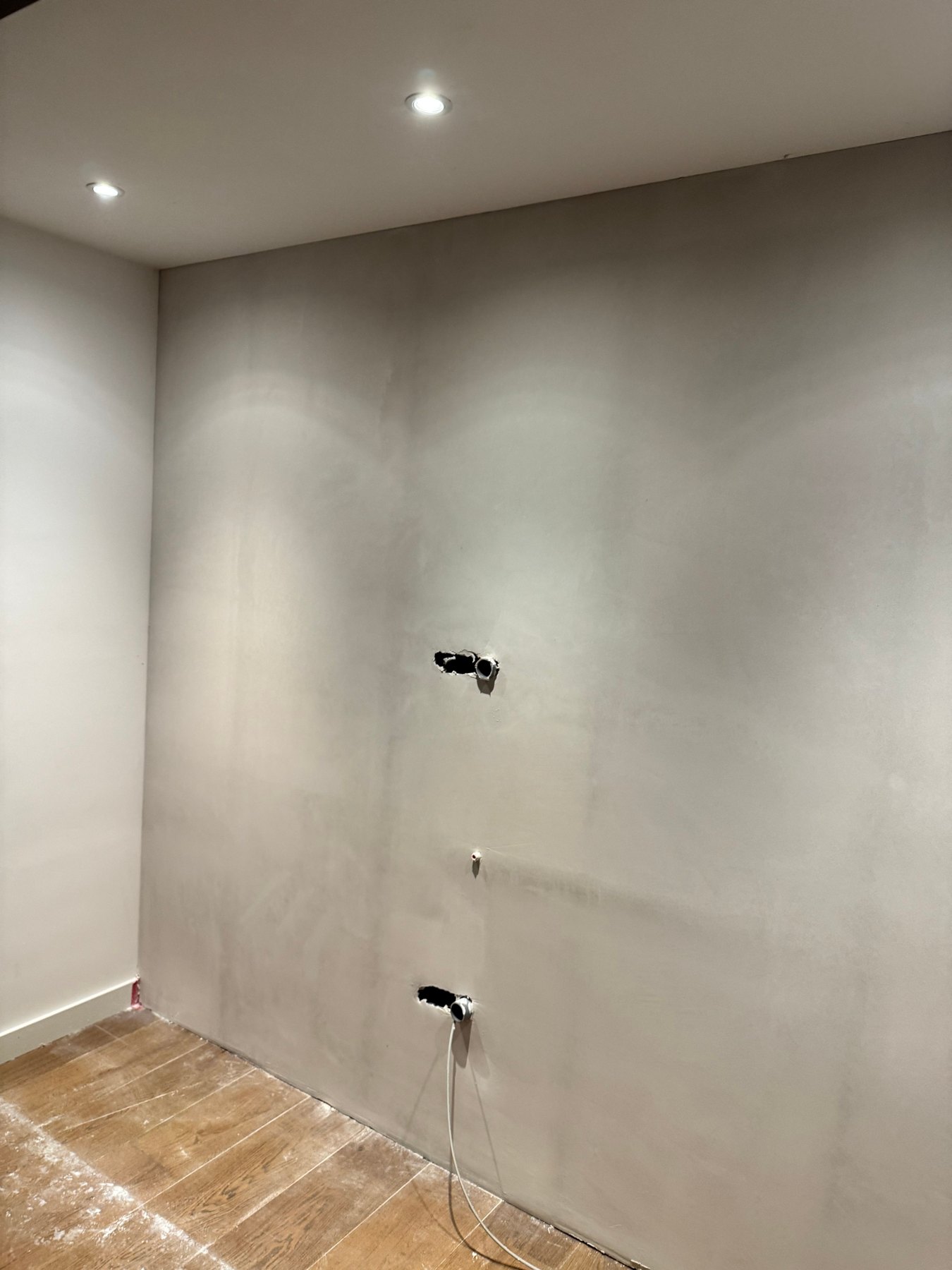 Vers gepleisterde badkamerwand met inbouwspots en aansluitpunten