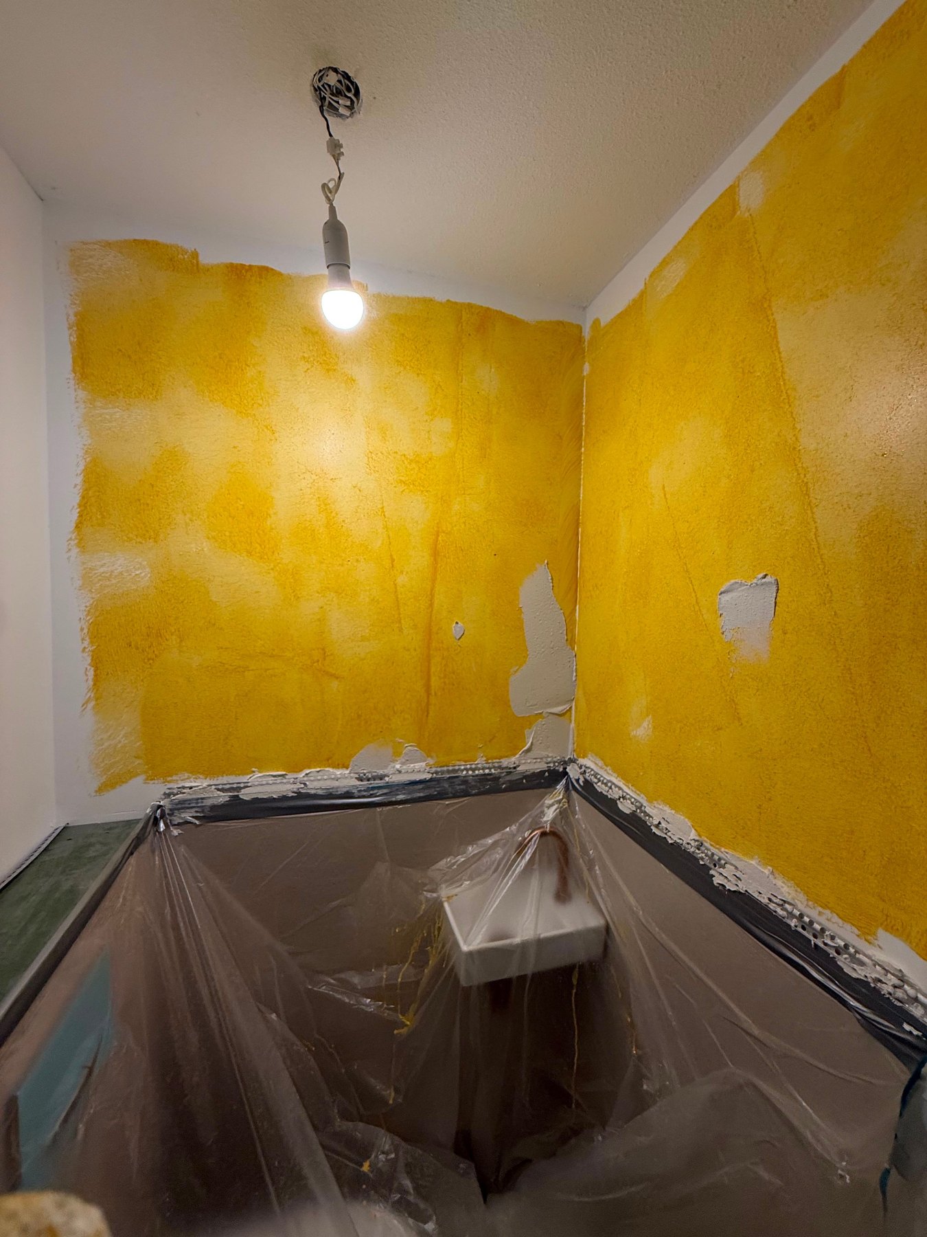 Toiletruimte voor het stucwerk, met geel gegronde wanden en afgedekt sanitair