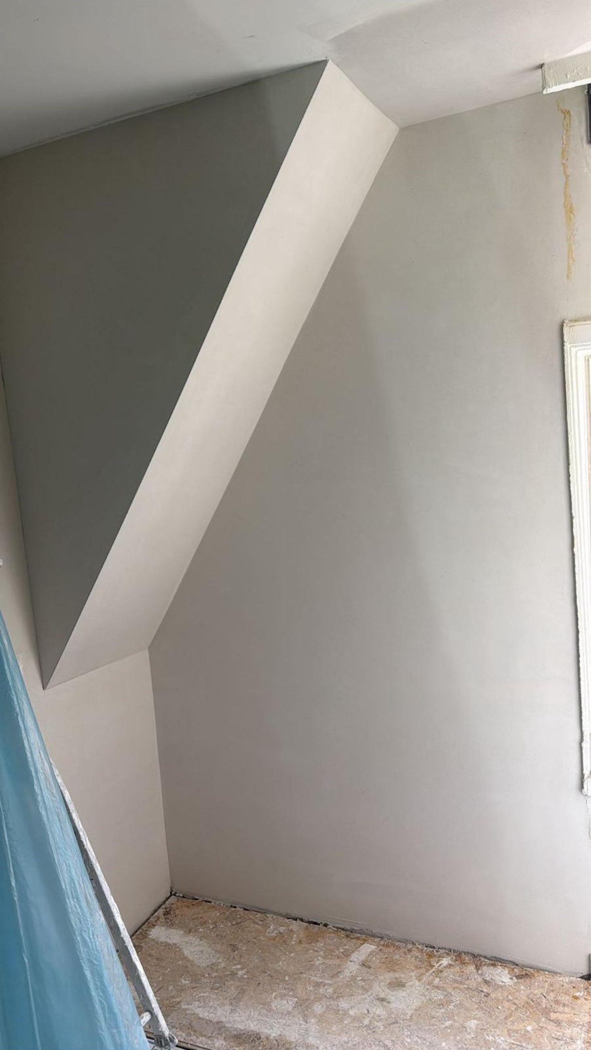 Zolderkamer tijdens het werk, met gestucte schuine wanden en afgedekte vloer